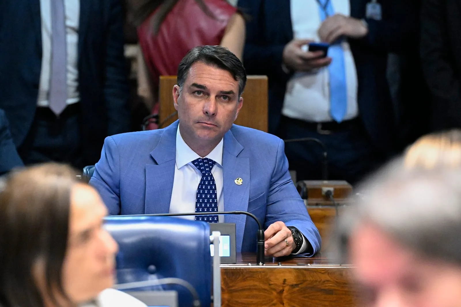 O senador Flávio Bolsonaro, de terno, sentado à bancada do Plenário do Senado Federal, entre outros parlamentares, durante sessão em Brasília.